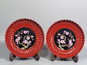 Qing Dynasty Qianlong coral red ground black ground pastel plum blossom melon petal plate
