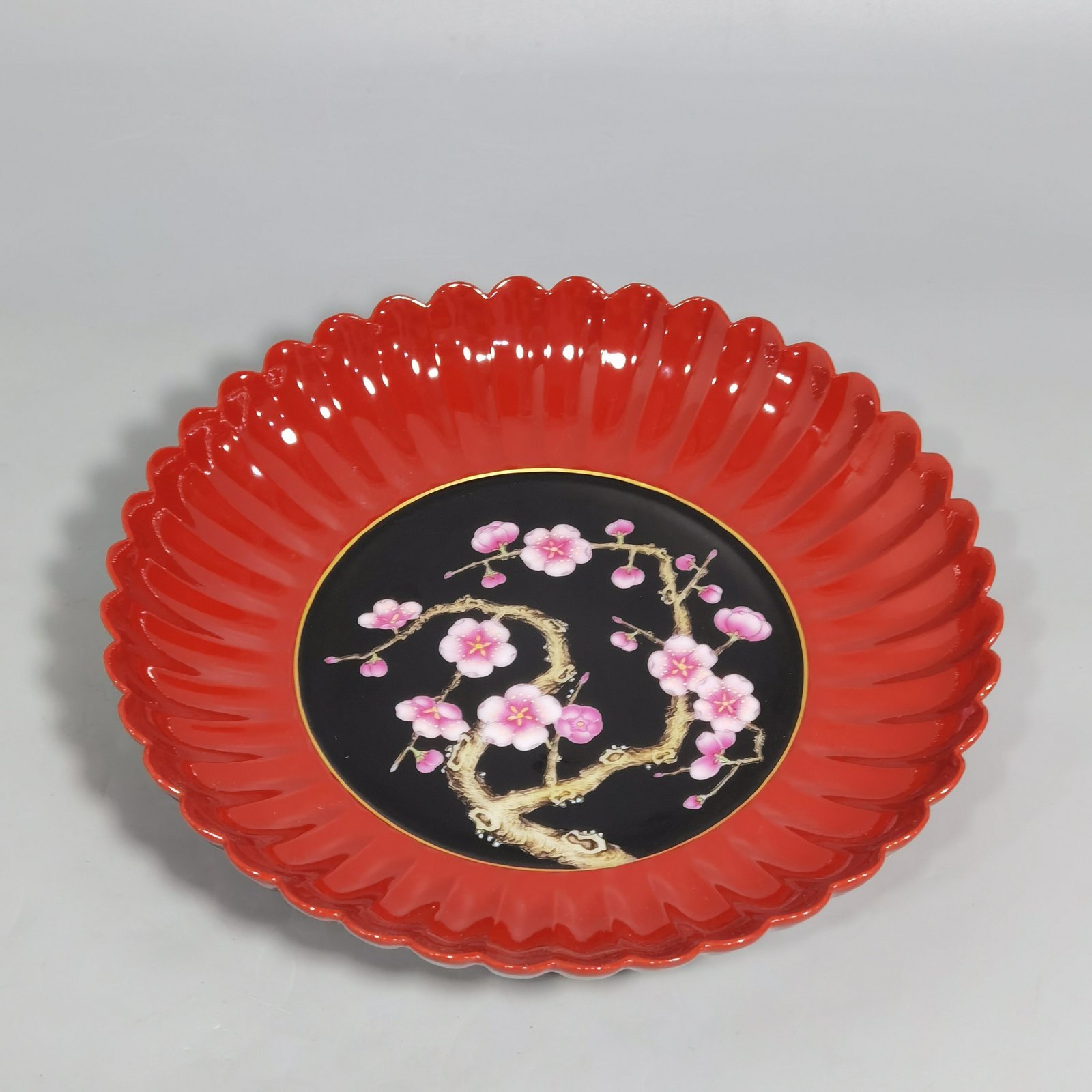 Qing Dynasty Qianlong coral red ground black ground pastel plum blossom melon petal plate