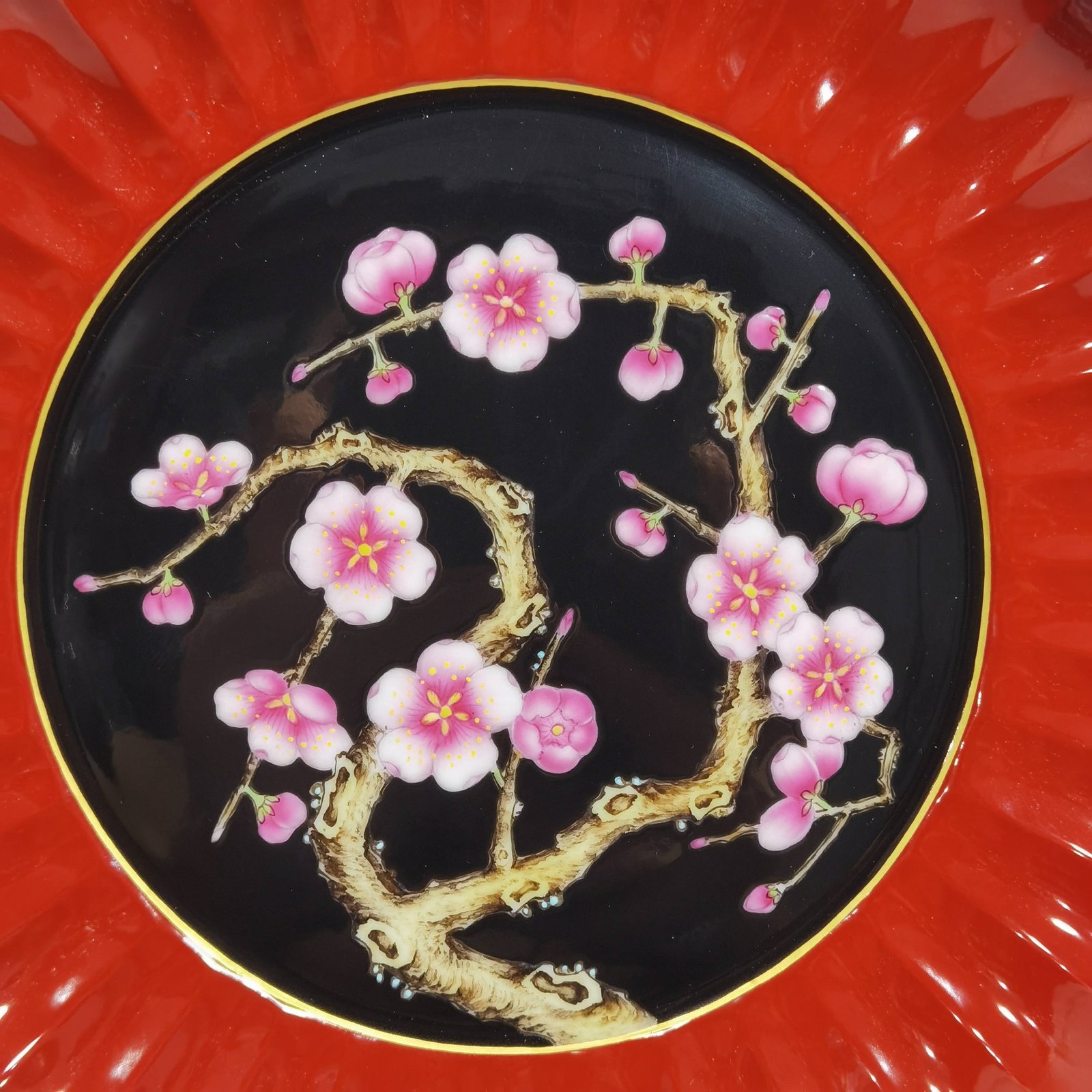 Qing Dynasty Qianlong coral red ground black ground pastel plum blossom melon petal plate