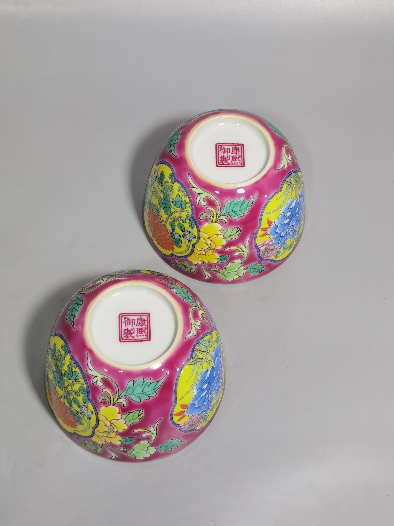 Qing Dynasty Kangxi pair of enamel and rouge ground consecrated cups with floral patterns