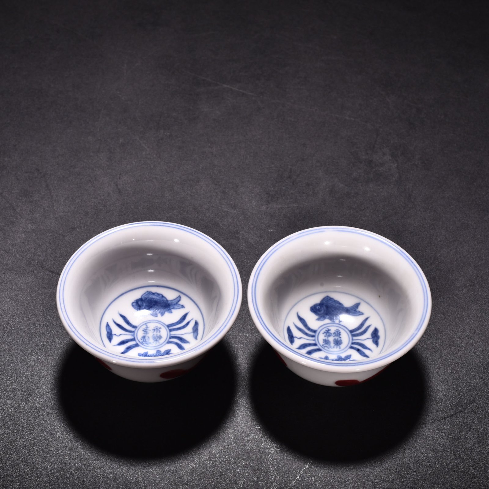 Ming Dynasty Xuande blue and white underglaze red fish and algae pattern three-fish pressing cup