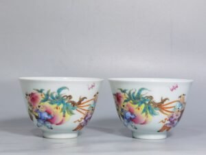 Qing Dynasty Yongzheng pair of pastel-painted boys presenting peaches and poems with tea balls