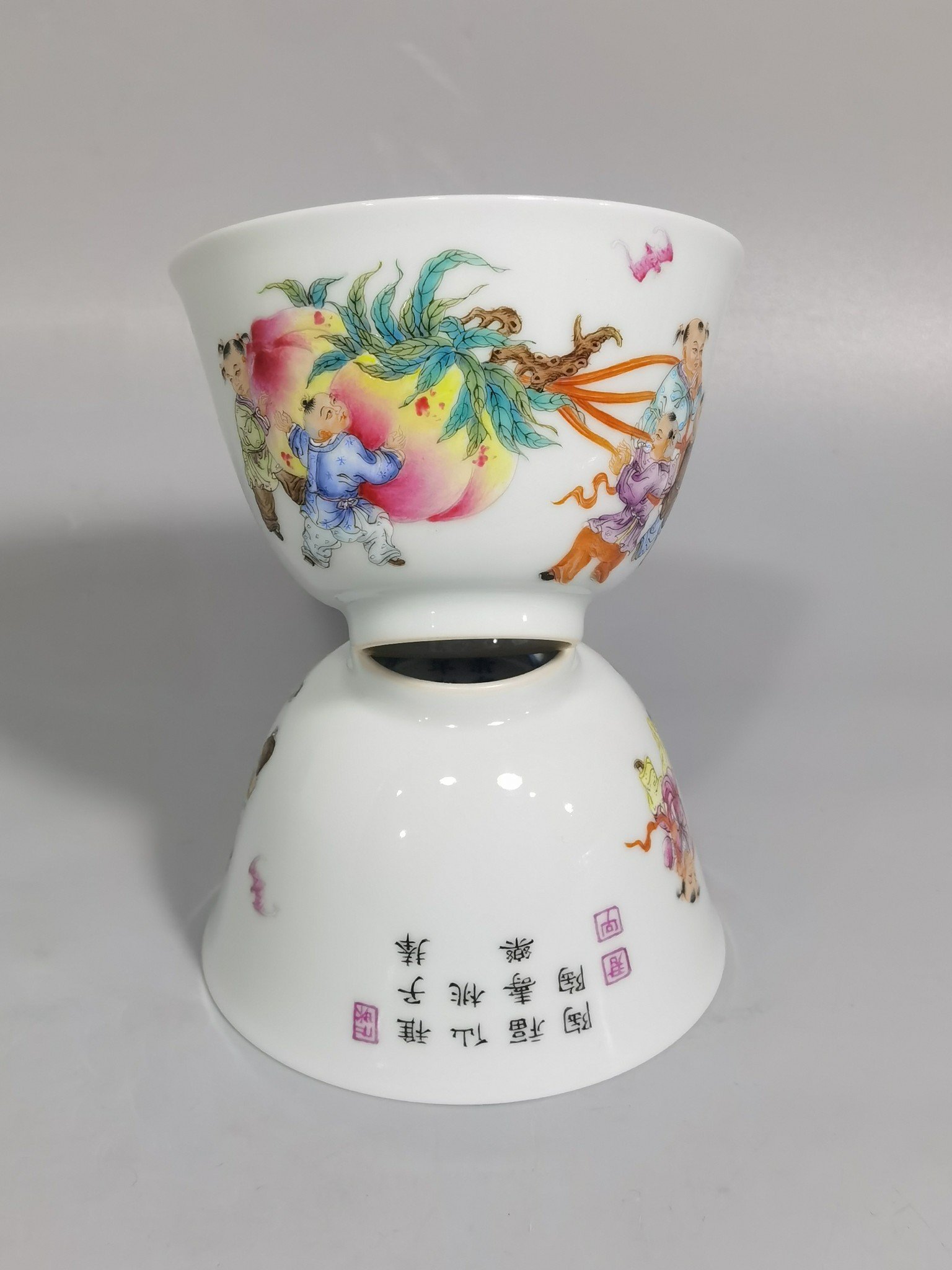 Qing Dynasty Yongzheng pair of pastel-painted boys presenting peaches and poems with tea balls