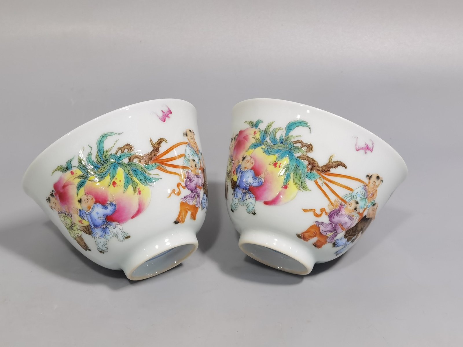 Qing Dynasty Yongzheng pair of pastel-painted boys presenting peaches and poems with tea balls