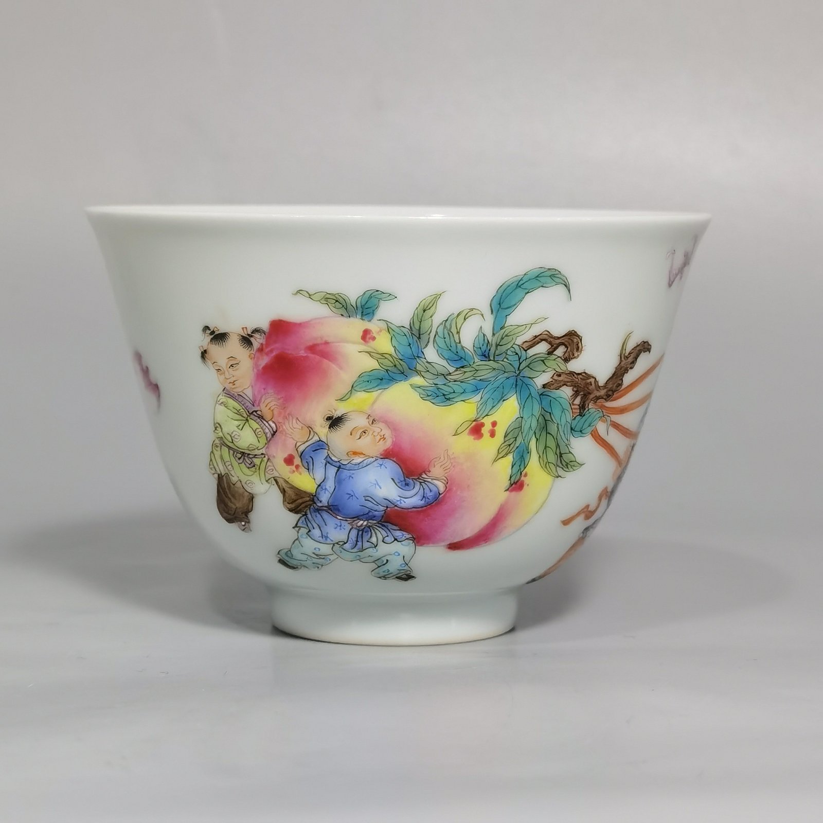 Qing Dynasty Yongzheng pair of pastel-painted boys presenting peaches and poems with tea balls