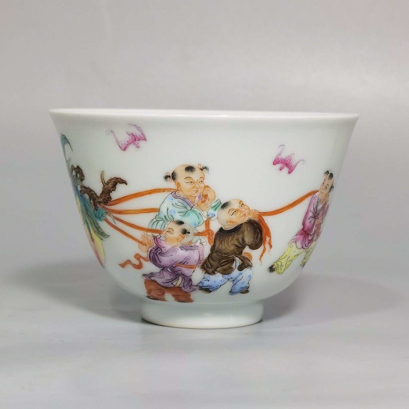Qing Dynasty Yongzheng pair of pastel-painted boys presenting peaches and poems with tea balls