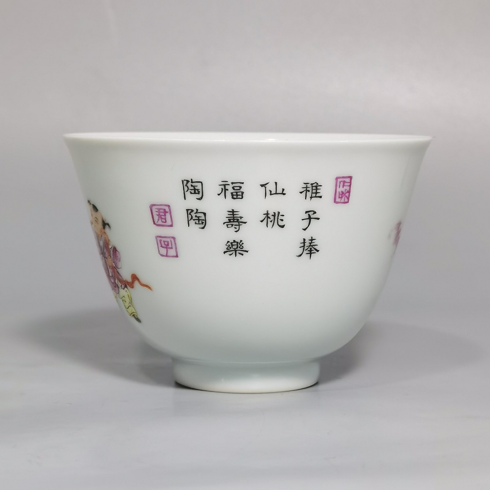 Qing Dynasty Yongzheng pair of pastel-painted boys presenting peaches and poems with tea balls